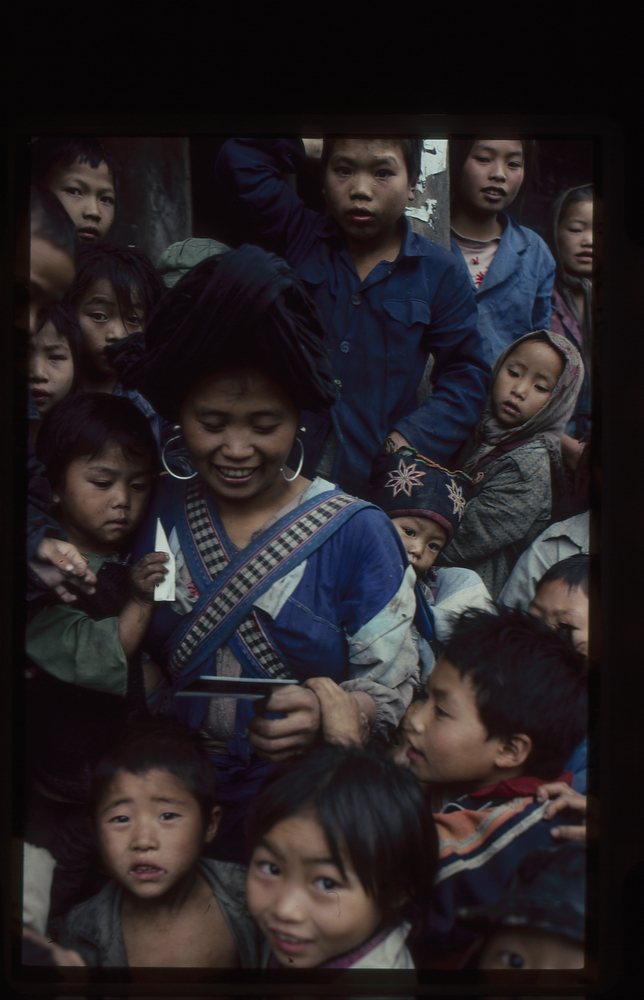 Image of 35mm slide: A woman looking at the Polaroid photograph given to her by Peter Baldwin. He gave such photos to most of his subjects. Film 6.