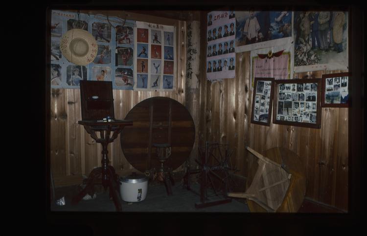 Image of 35mm slide: Photographs on the wall depicting military men, inside a shop or house