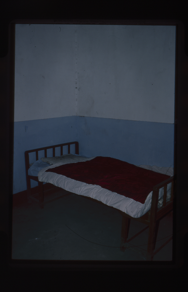 Image of 35mm slide: Bed in hotel room (Oct 10th – no mosquito net, one table’?)