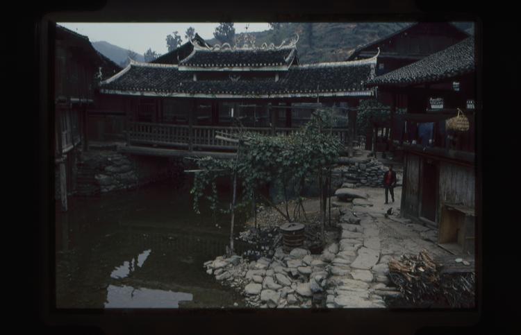 Image of 35mm slide: Scene in village with bridge across the river