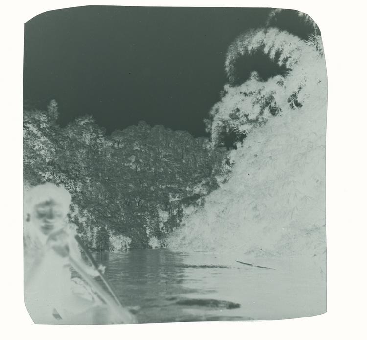 image of Black and white negative closeup of Wai Wai tribe member smiling and canoeing down river