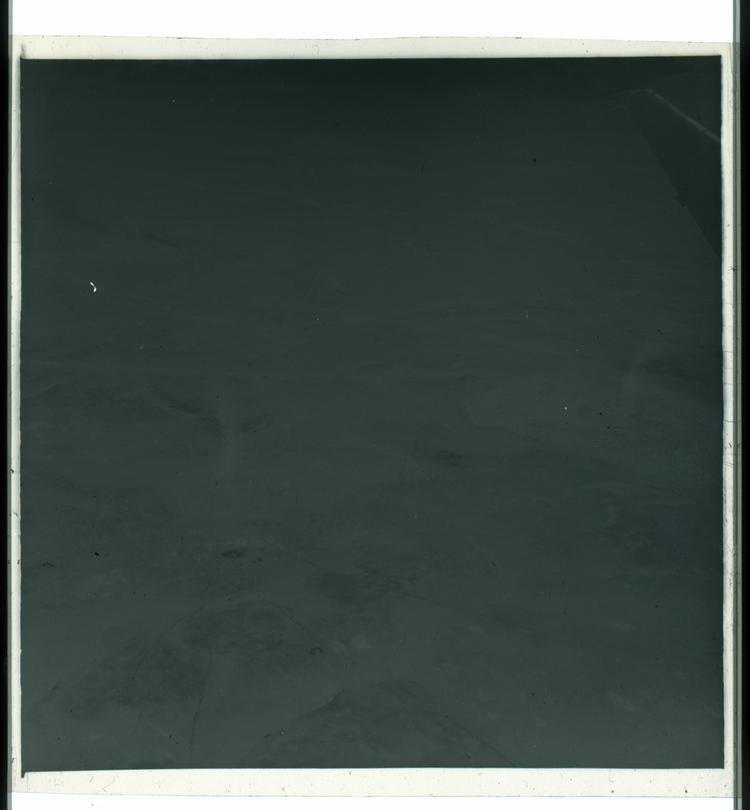image of Black and white negative view of ground from airplane with slight bit of wing in frame