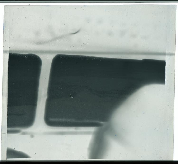 Image of Black and white negative view of ground through windows of airplane
