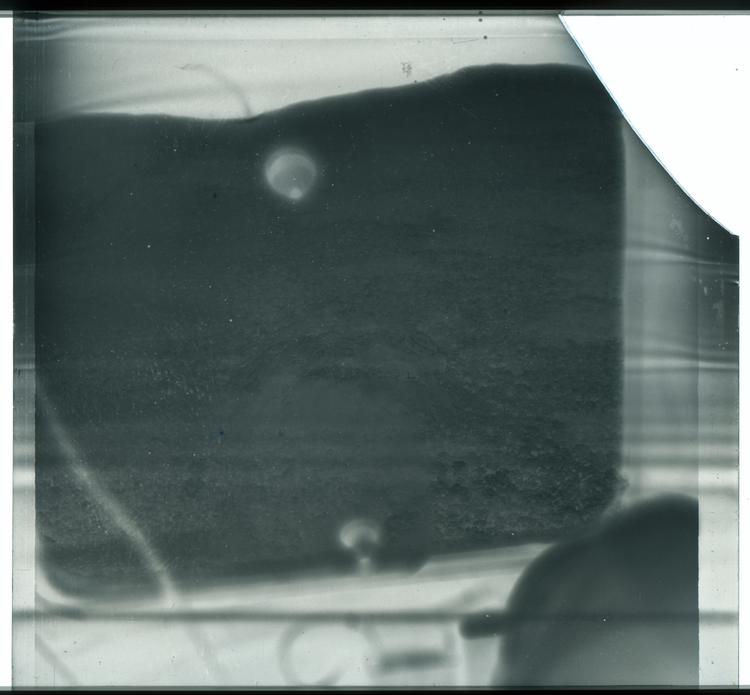 Image of Black and white negative view of ground through windows of airplane