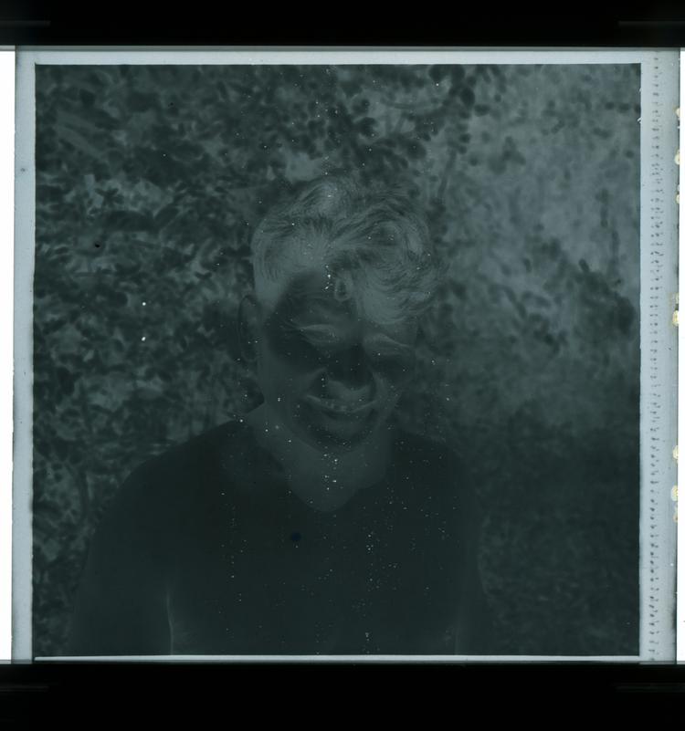 Image of Black and white negative close-up view of shirtless man smiling