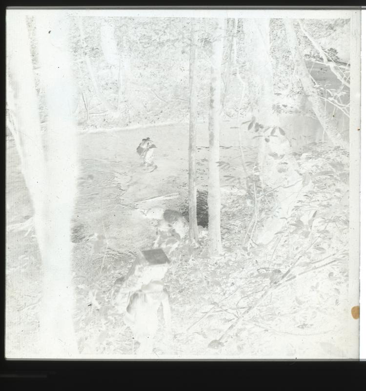 Image of Black and white negative of expedition members crossing river carrying rucksacks