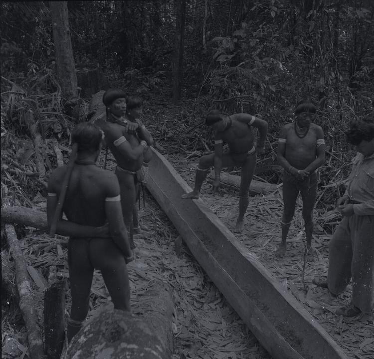 Image of Black and white negative of six men (five Wai Wai and one European) standing around a canoe