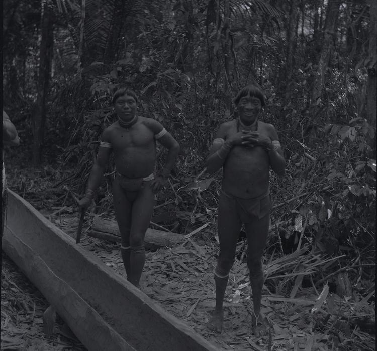 Image of Black and white negative of two Wai Wai men standing by a canoe