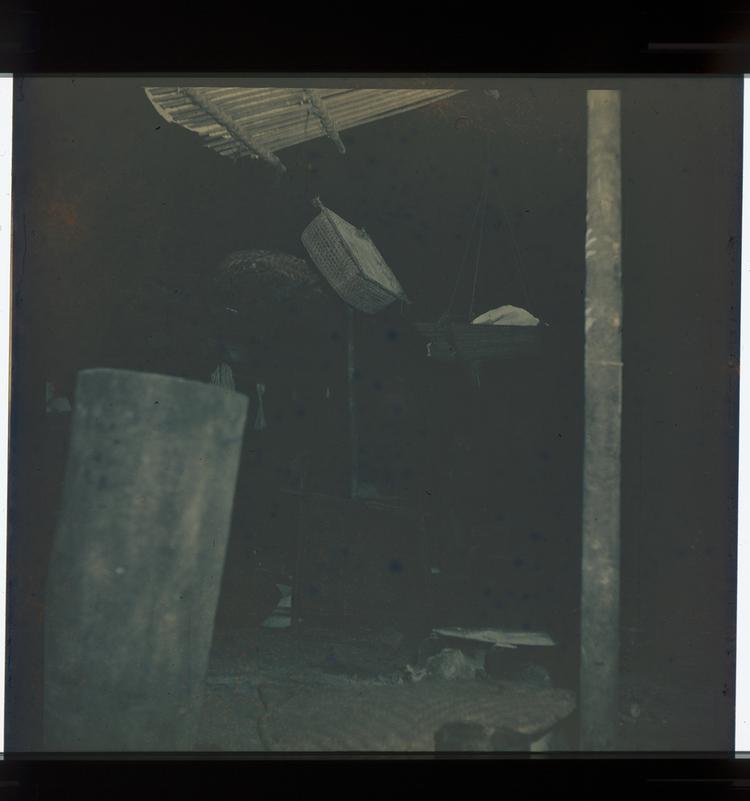 Image of Black and white negative of view into a Wai Wai hut with woven objects inside