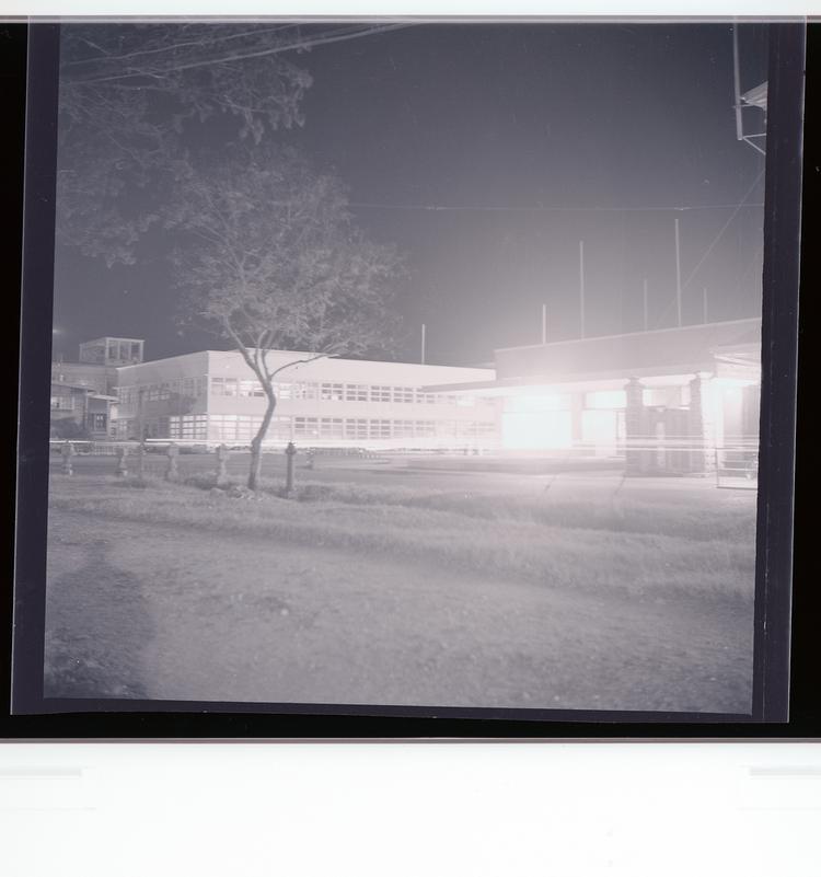 Image of Black and white negative of building with sparse trees in foreground