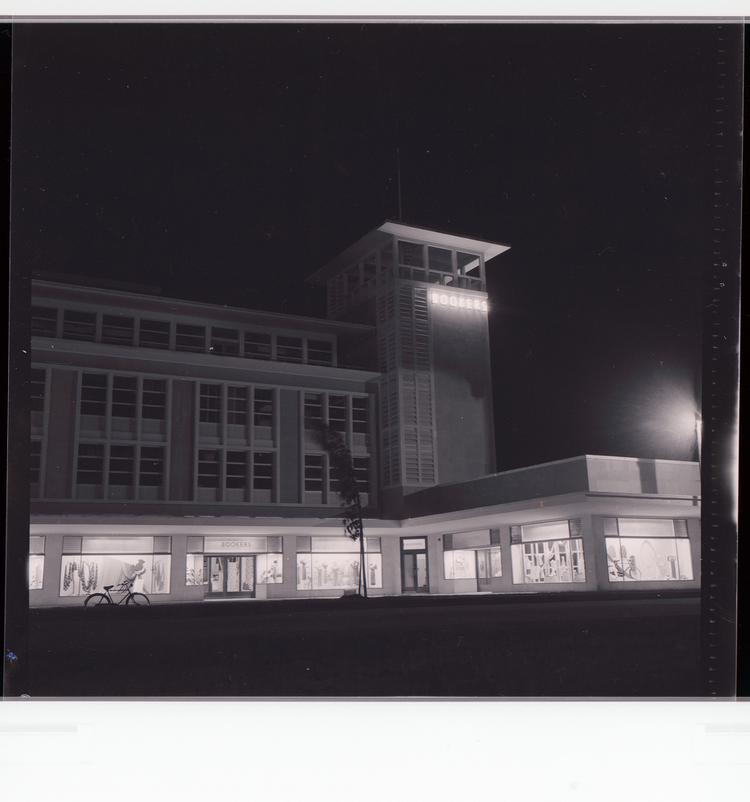 image of Black and white negative corner view of 'Bookers' building at night with 'Bookers' neon letters on side of tower