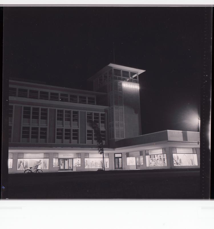 Image of Black and white negative corner view of 'Bookers' building at night with 'Bookers' neon letters on side of tower