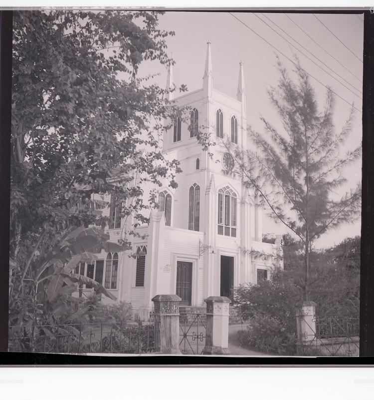 Image of Black and white negative side-angled view of ornate church framed by trees