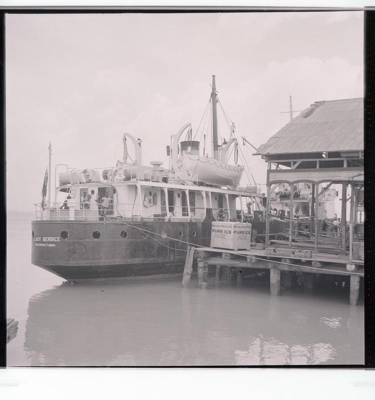 Image of Black and white negative of Lady Berbice ship docked next to building