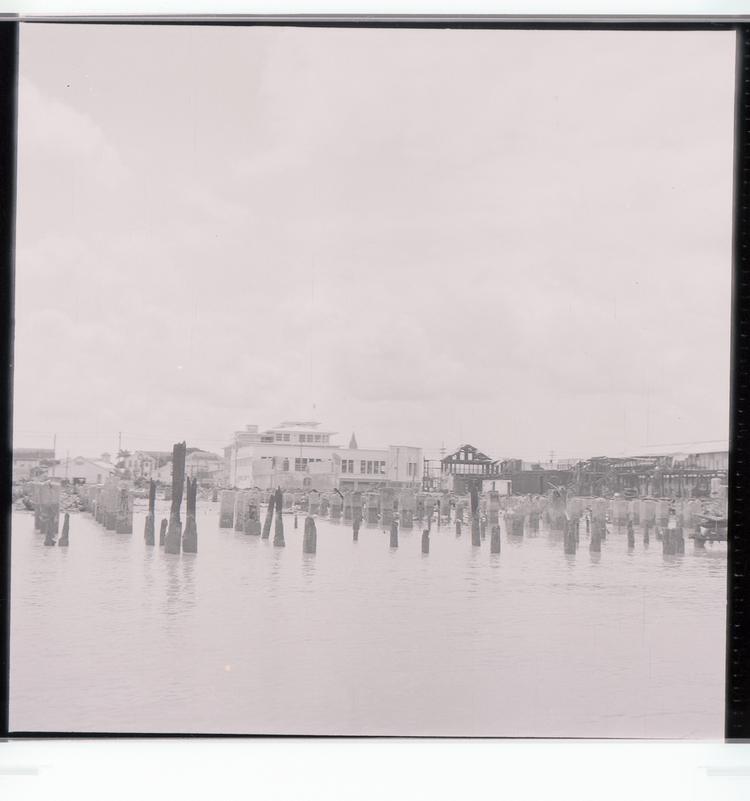 Image of Black and white negative view of burned dockside buildings and harbour