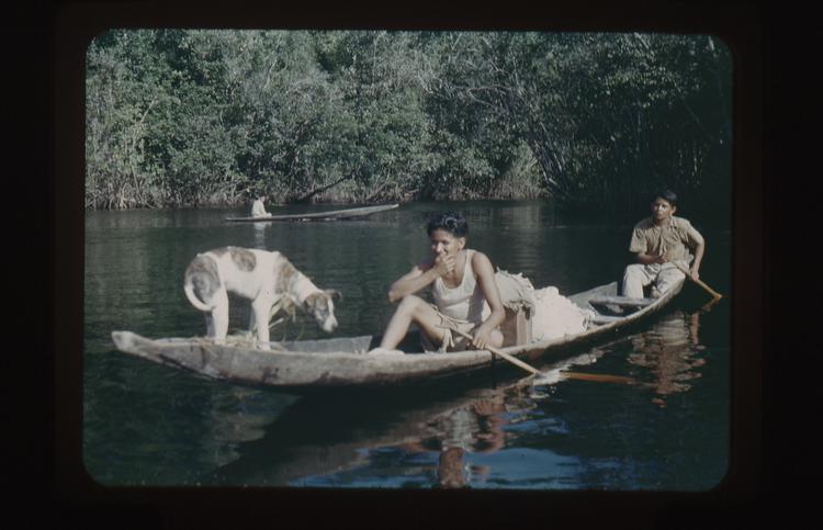 image of Color 35mm positive film of two men and one dog in a low canoe on a river, with one man in a canoe in background