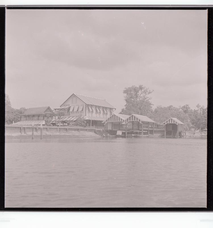 image of Black and white negative of multiple striped buildings with dock on water