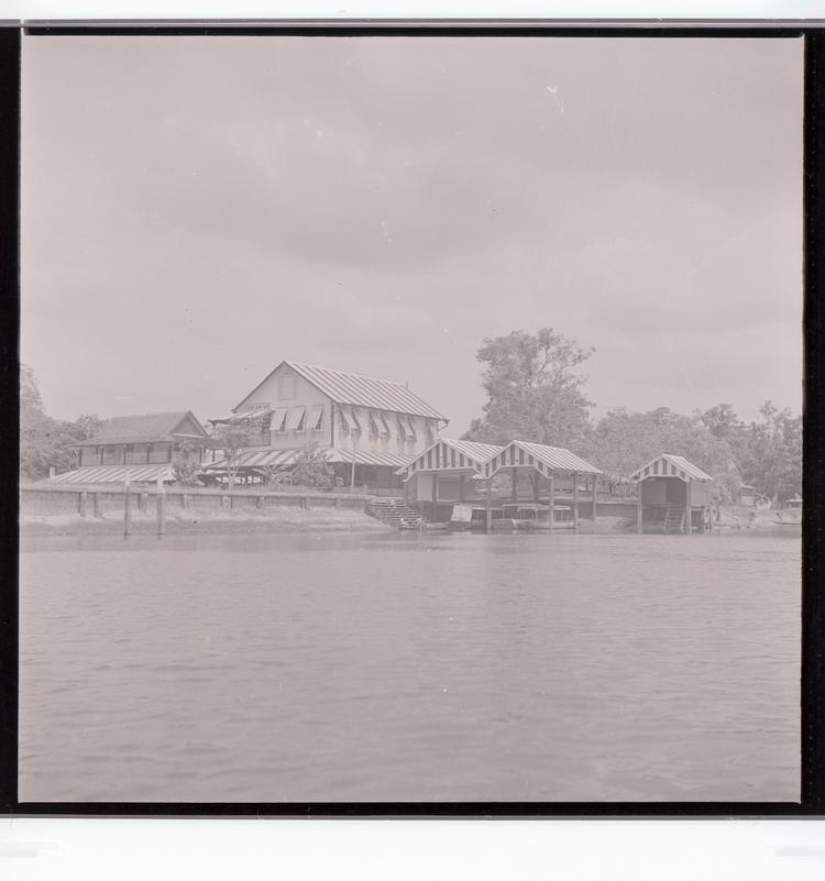 Image of Black and white negative of multiple striped buildings with dock on water