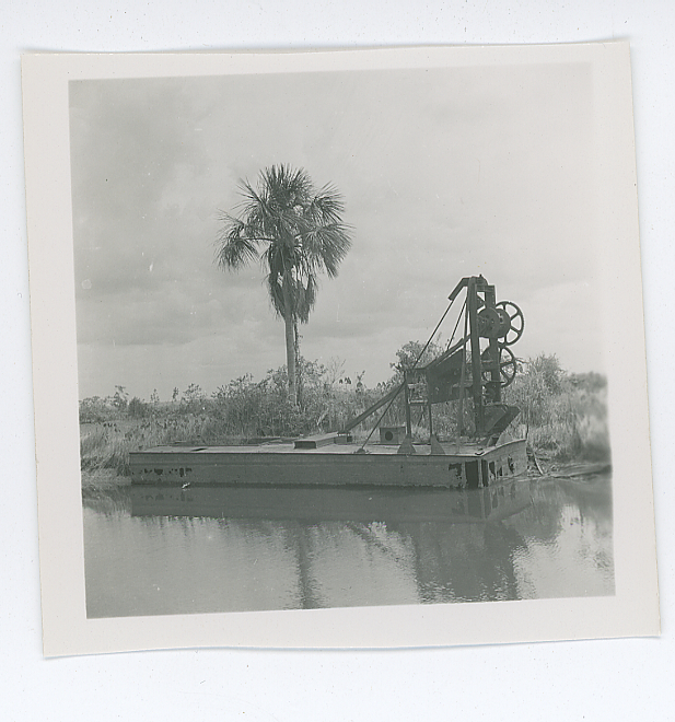 Image of Black and white negative of trees on horizon with wetlands and small motorboats in foreground