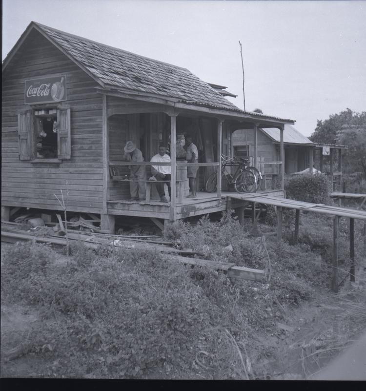 Image of Black and white medium format negative (scanned positive)of a shop with people on a veranda