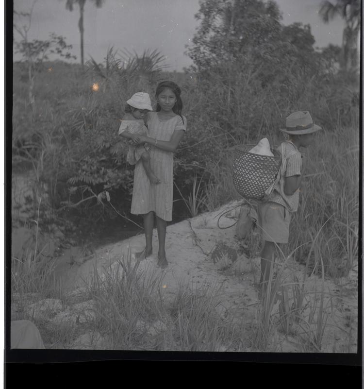 image of Black and white medium format negative (scanned positive) a girl and boy standing on a rocky area -the girl is holding a baby