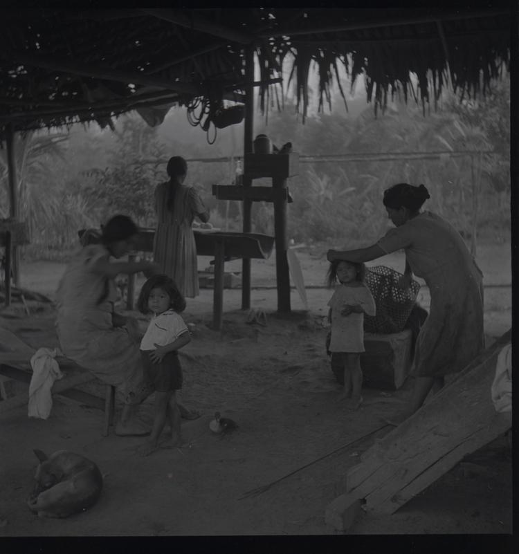 Image of Black and white medium format negative (scanned positive) 3 women and 2 small girls having their hair tidied in a hut