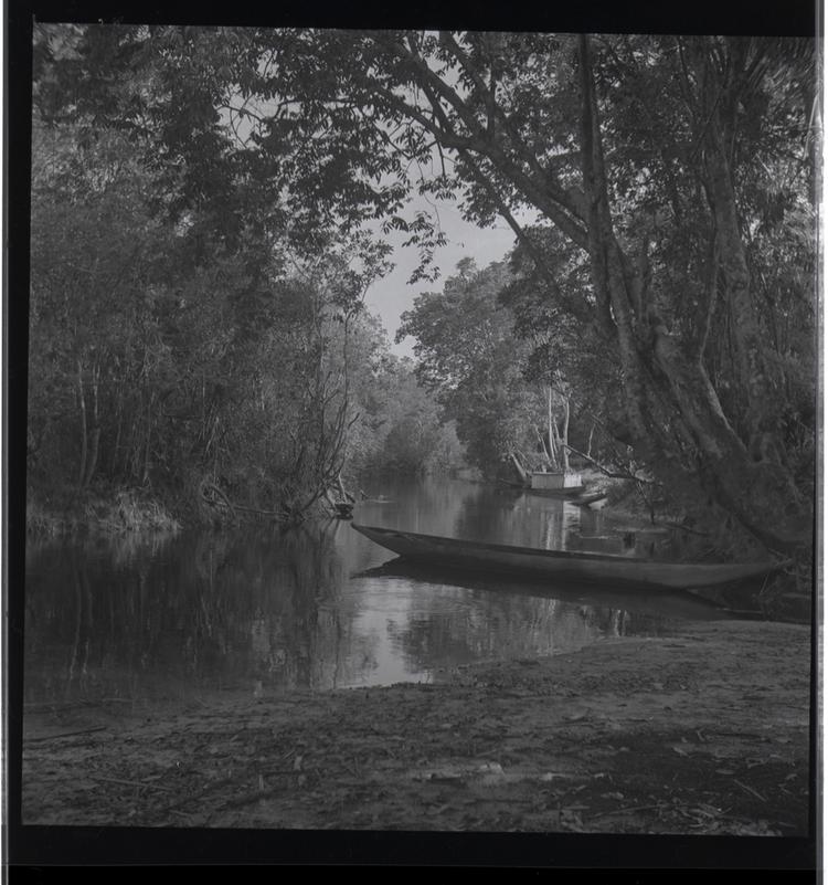 image of Black and white medium format negative (scanned positive) of river with moored canoe