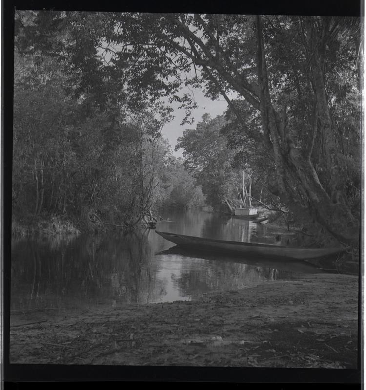 Image of Black and white medium format negative (scanned positive) of river with moored canoe