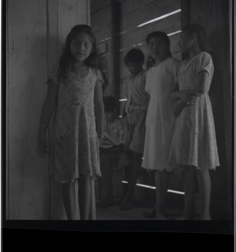 Image of Black and white medium format negative (scanned positive) young girl by door with others nearby