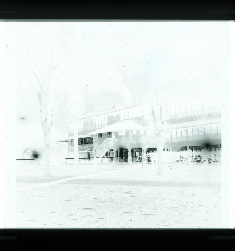 Image of Black and white negative of white multi-storey house on stilts, view at night, back view