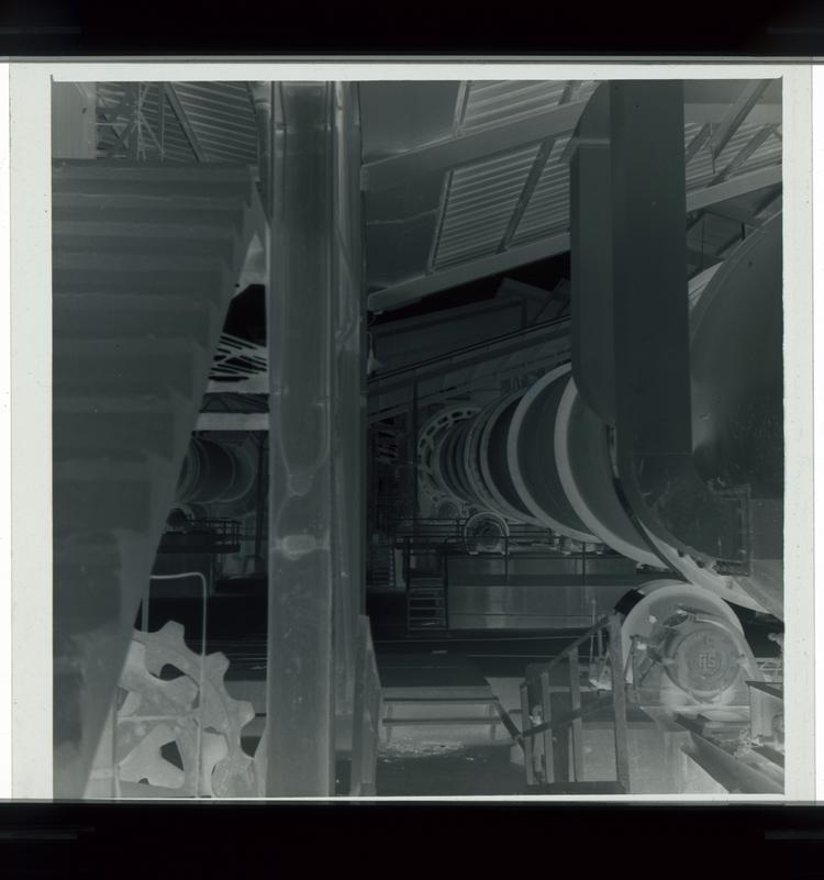 image of Black and white negative of large cylinder in factory setting