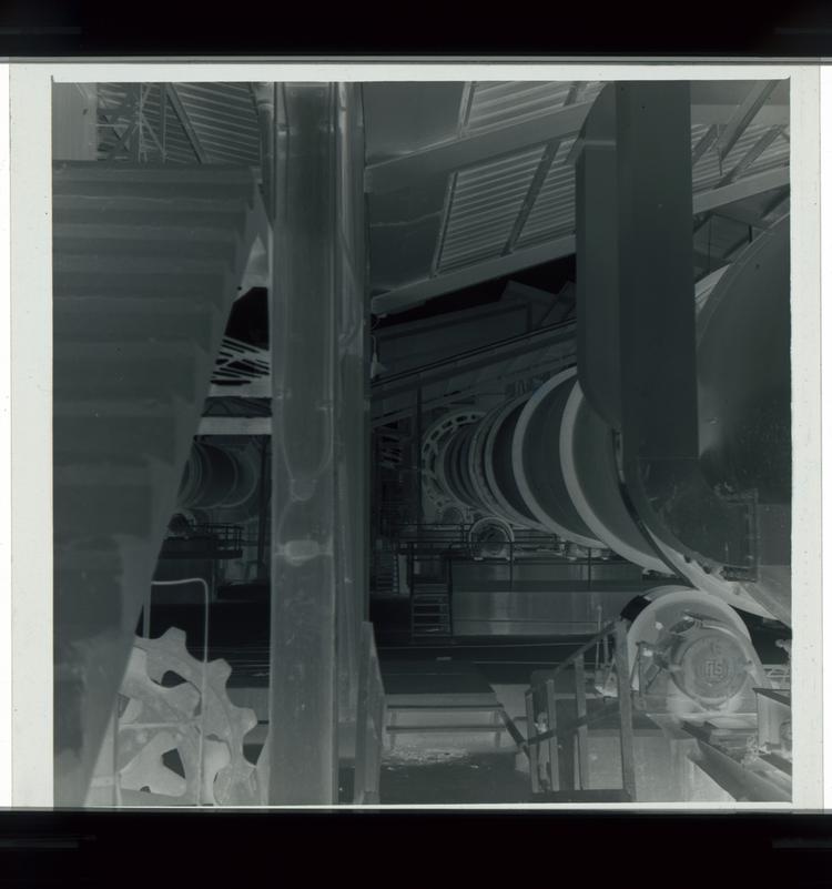 Image of Black and white negative of large cylinder in factory setting