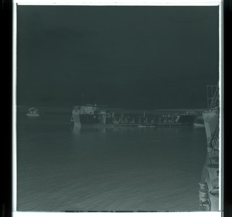 image of Black and white negative of barge boat on water, from perspective of another boat on the water