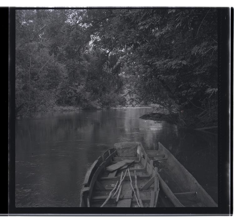 Black and white medium format negative of two empty boats on river (apart from oars in larger boat)