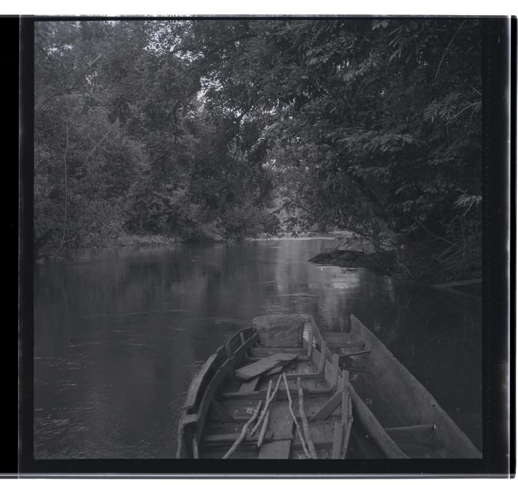 Image of Black and white medium format negative of two empty boats on river (apart from oars in larger boat)