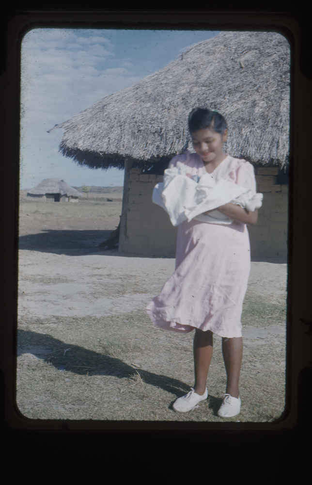 Image of Colour slide of woman in pink dress holding a baby