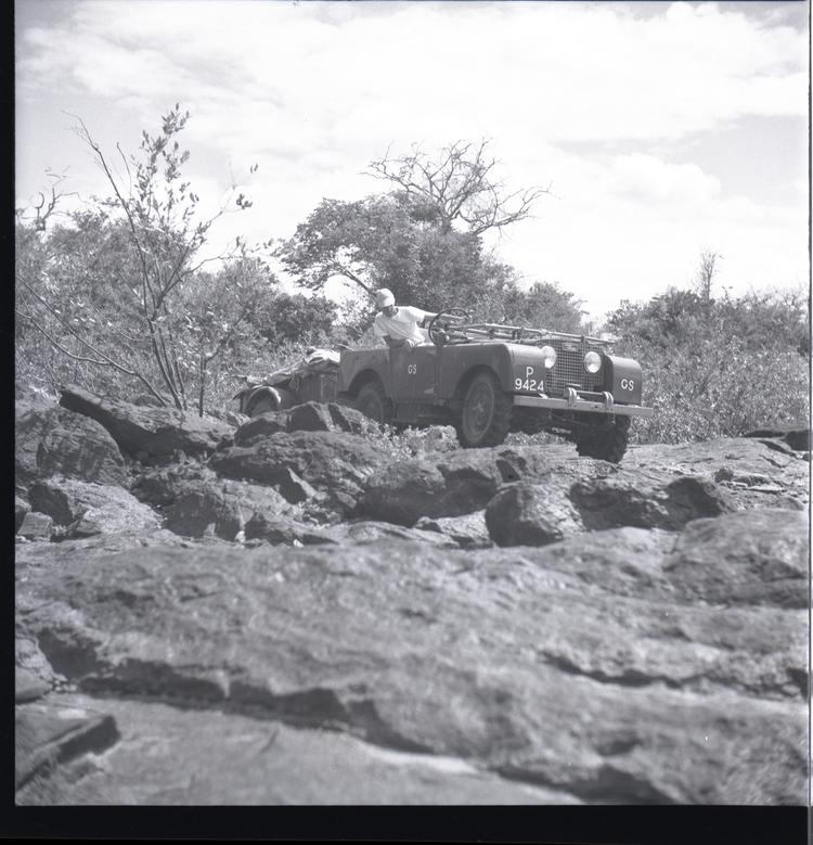 Black and white medium format negative of jeep with trailer on very rocky ground