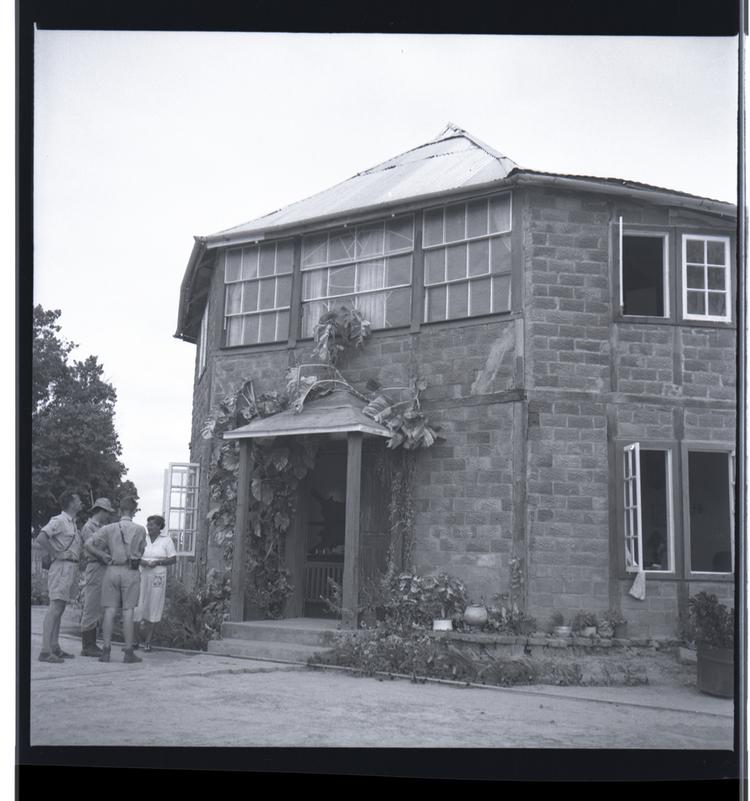 image of Black and white medium format negative of brick built two storey house with porch and glazed windows with four people outside