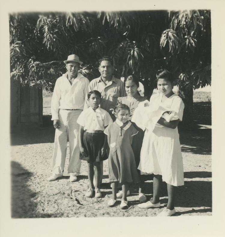 Image of Black and white print of a group of people - four adults, two children and a baby