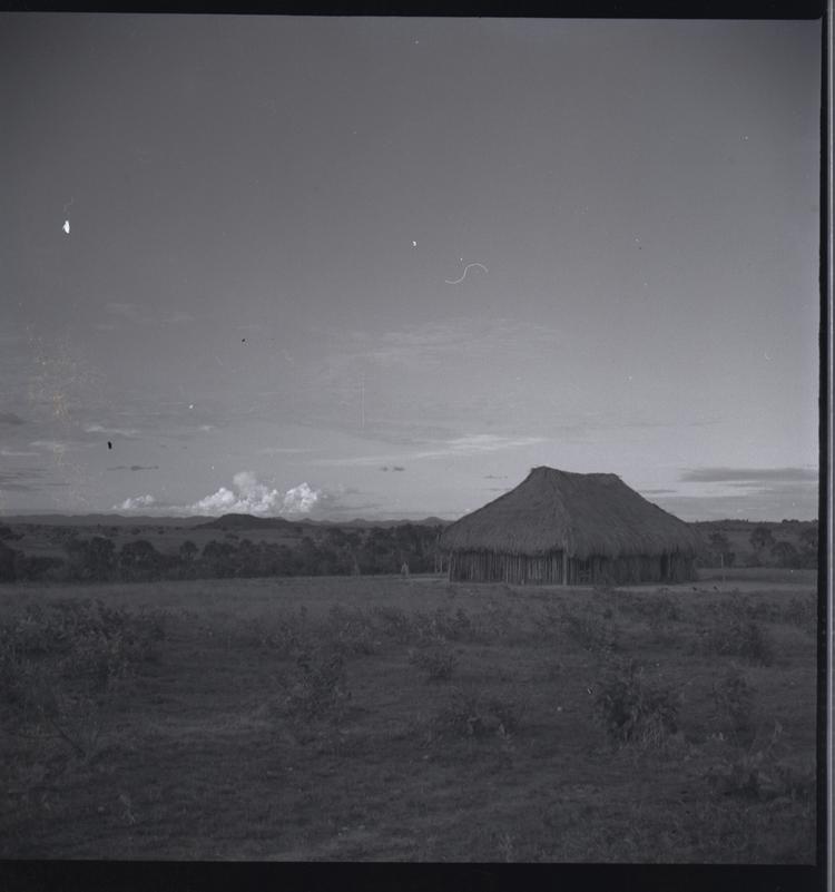 image of Black and white medium format negative of large hut style building in flat landscape