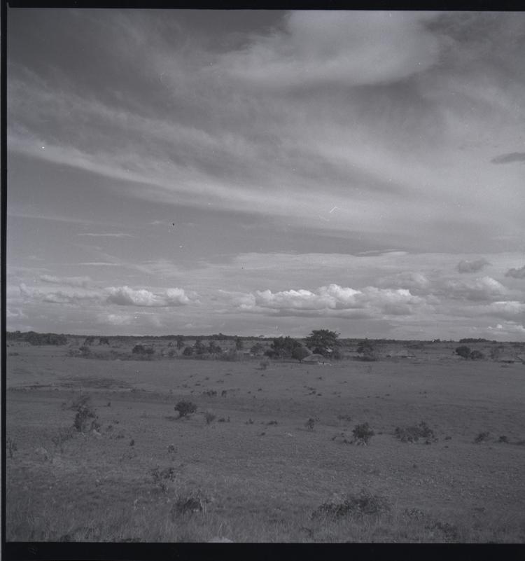 Image of Black and white medium format negative of village of hut style houses in distance