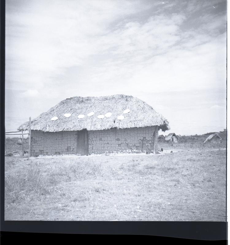image of Black and white medium format negative of hut in foreground with two more in the background