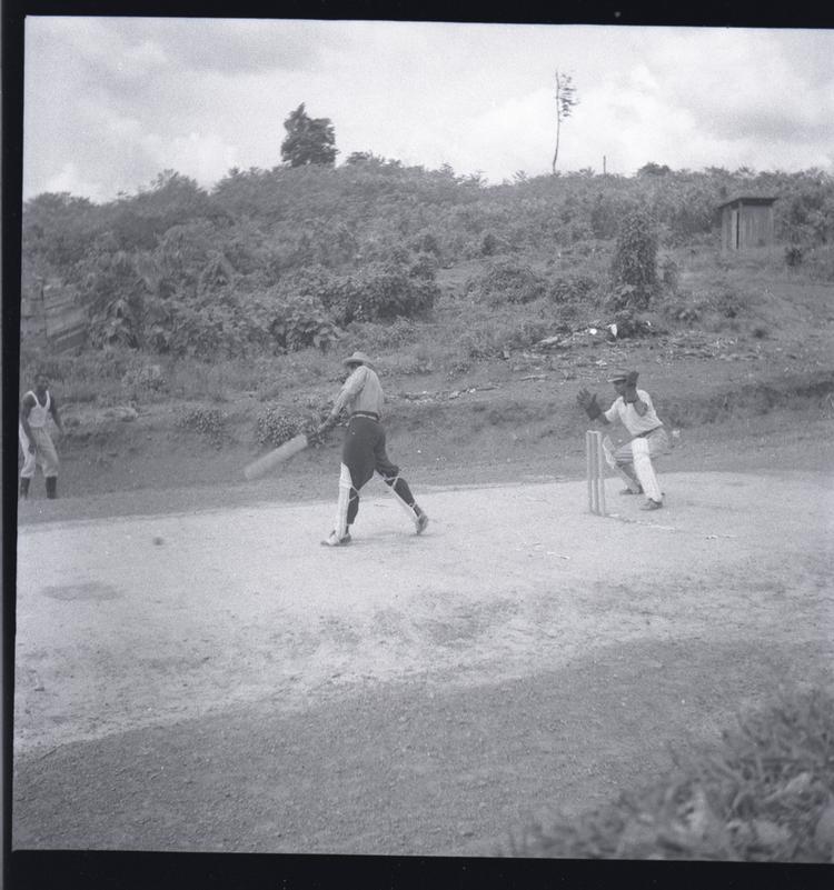 image of Black and white medium format negative of three men playing cricket (2 wearing batting pads)
