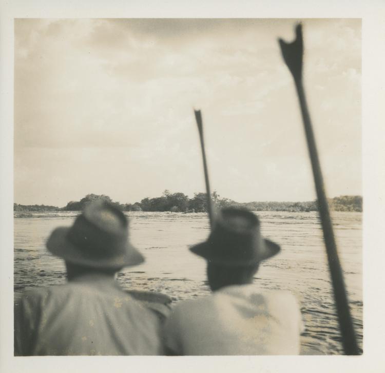 image of Black and white print of two men in hats on a boat looking down river