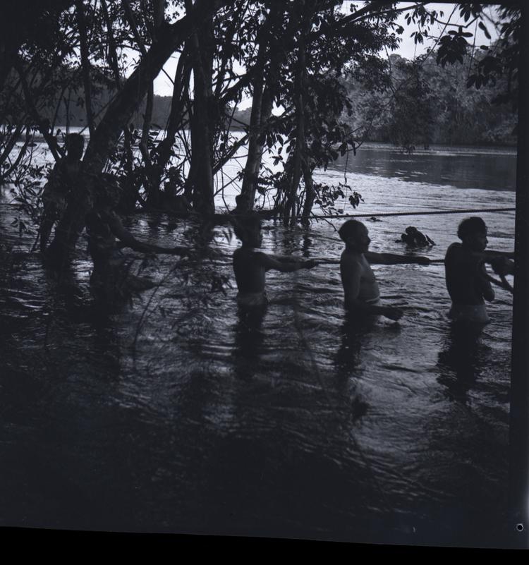 Black and white medium format negative of men in water hauling on rope