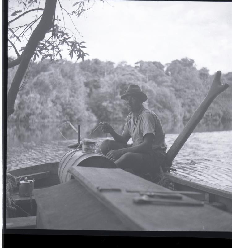 image of Black and white medium format negative of man wearing hat sitting on a boat