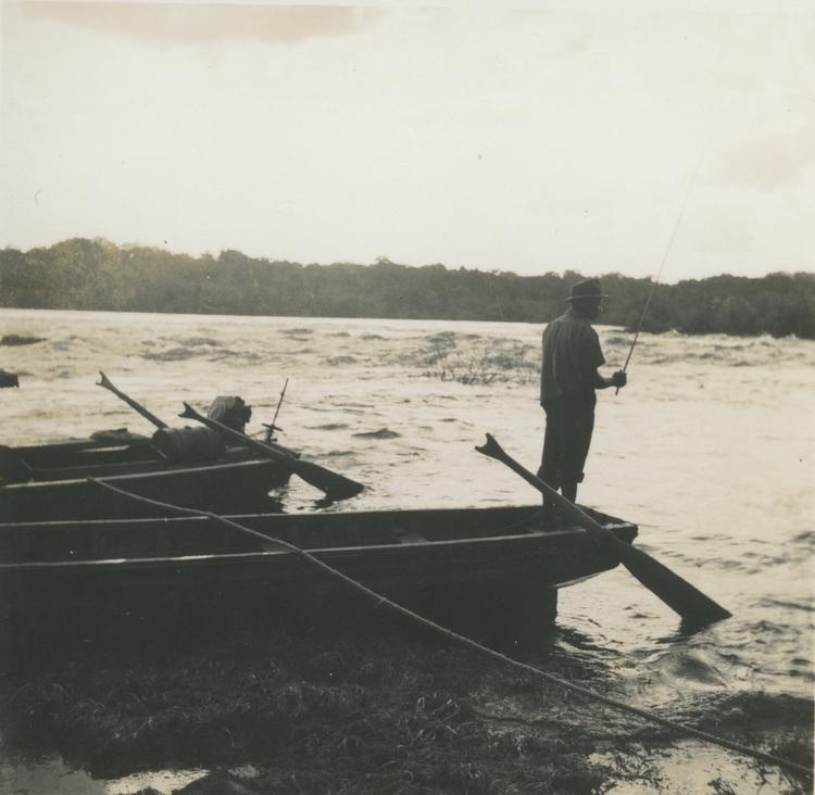 image of Black and white print of man standing on a boat fishing