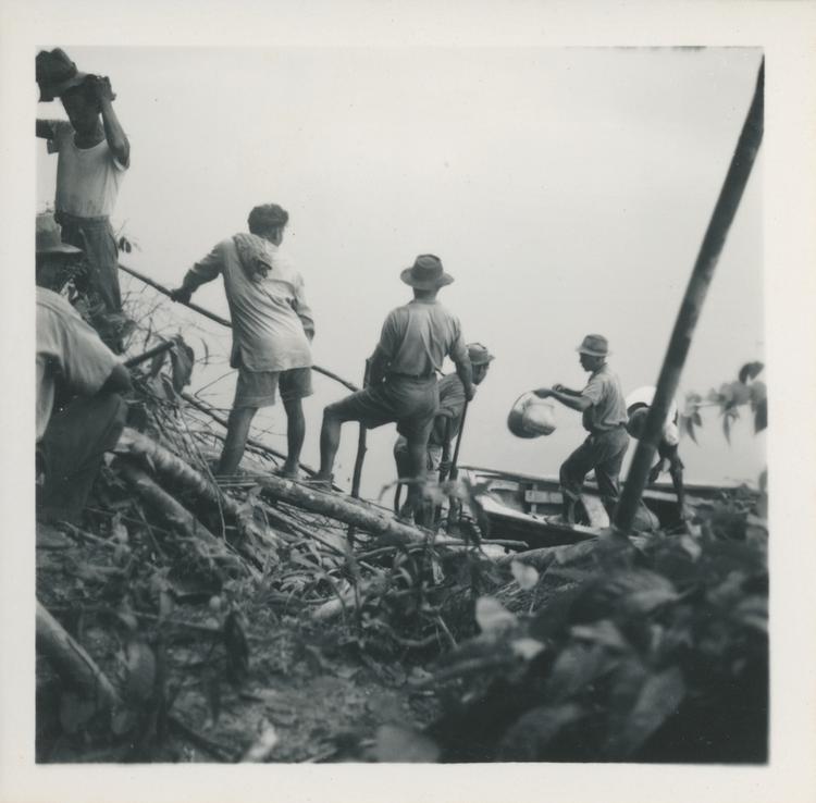 Image of Black and white print chain of men loading a boat