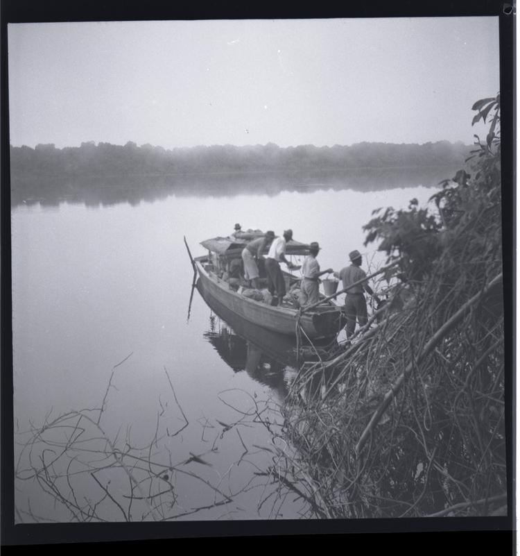 image of Black and white medium format negative of loaded boat leaving bank side with misty view across wide river