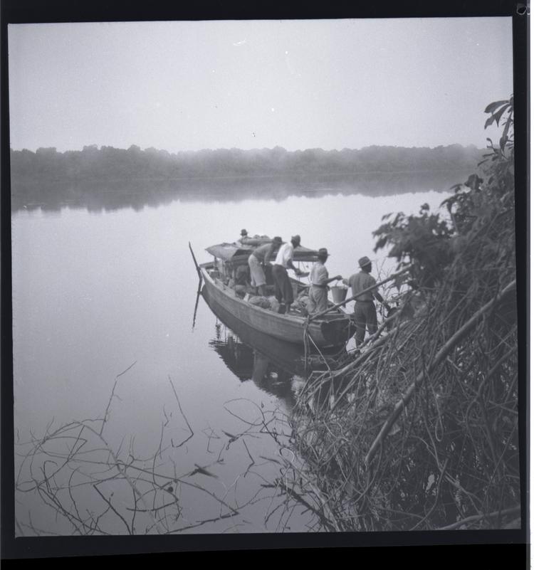 Image of Black and white medium format negative of loaded boat leaving bank side with misty view across wide river